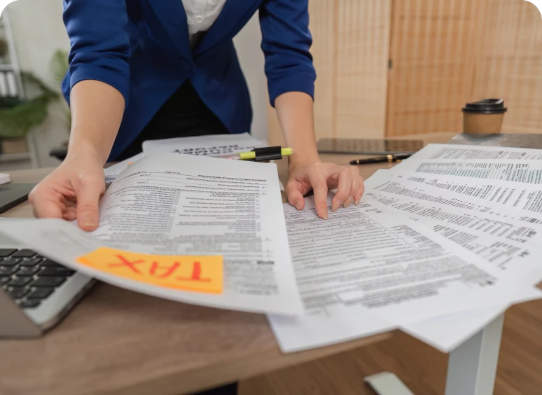 Hands sorting tax paperwork with calculator